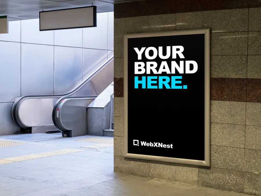 A lit poster screen in a station underpass reading Your Brand Here.