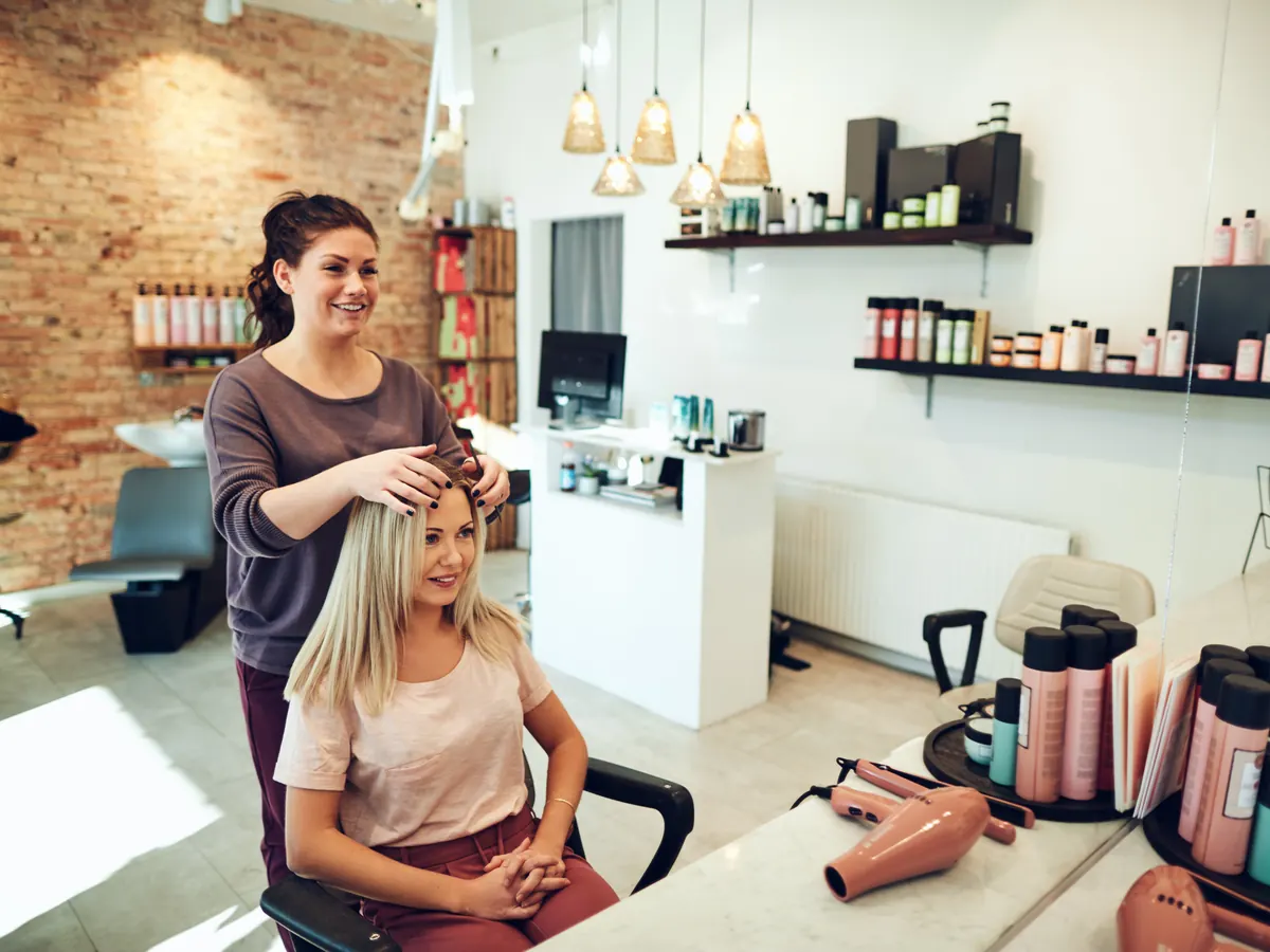 A stylist working on a client&rsquo;s hair in a salon.