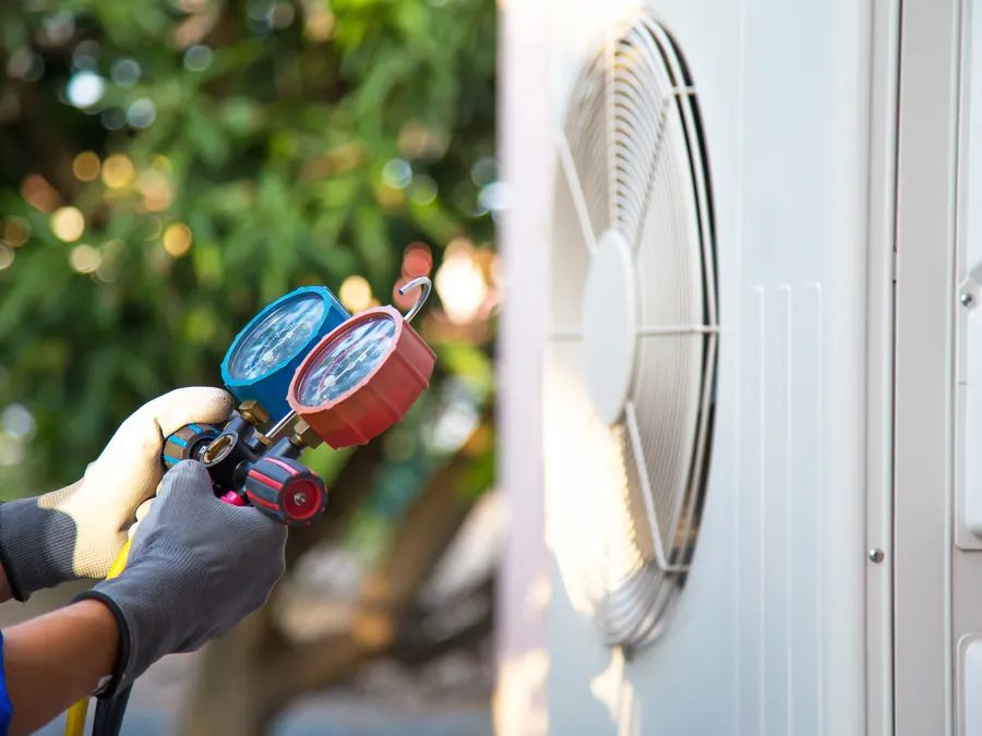 An HVAC technician checking an air conditioner.
