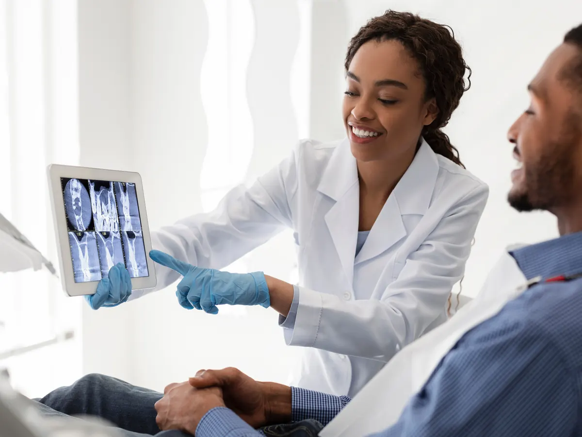 A dentist showing a patient an X-ray on a tablet.