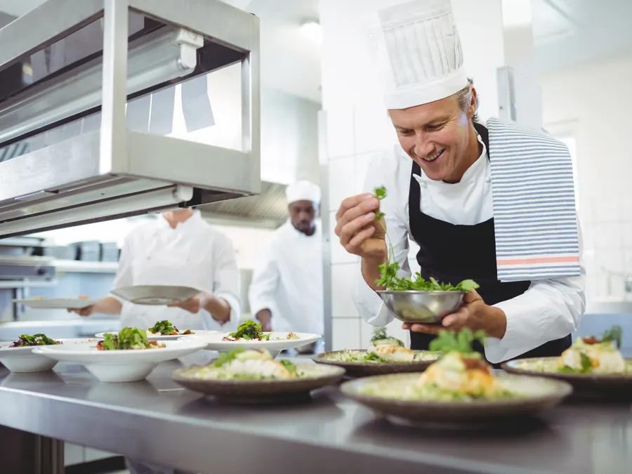 A chef garnishing plates at the pass.