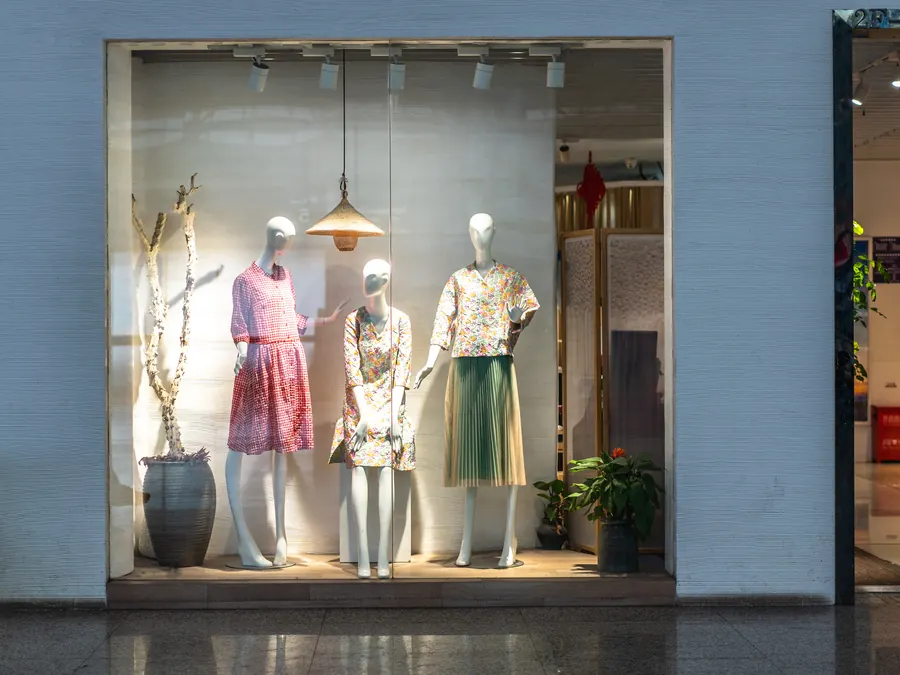 Dresses on mannequins in a boutique window.