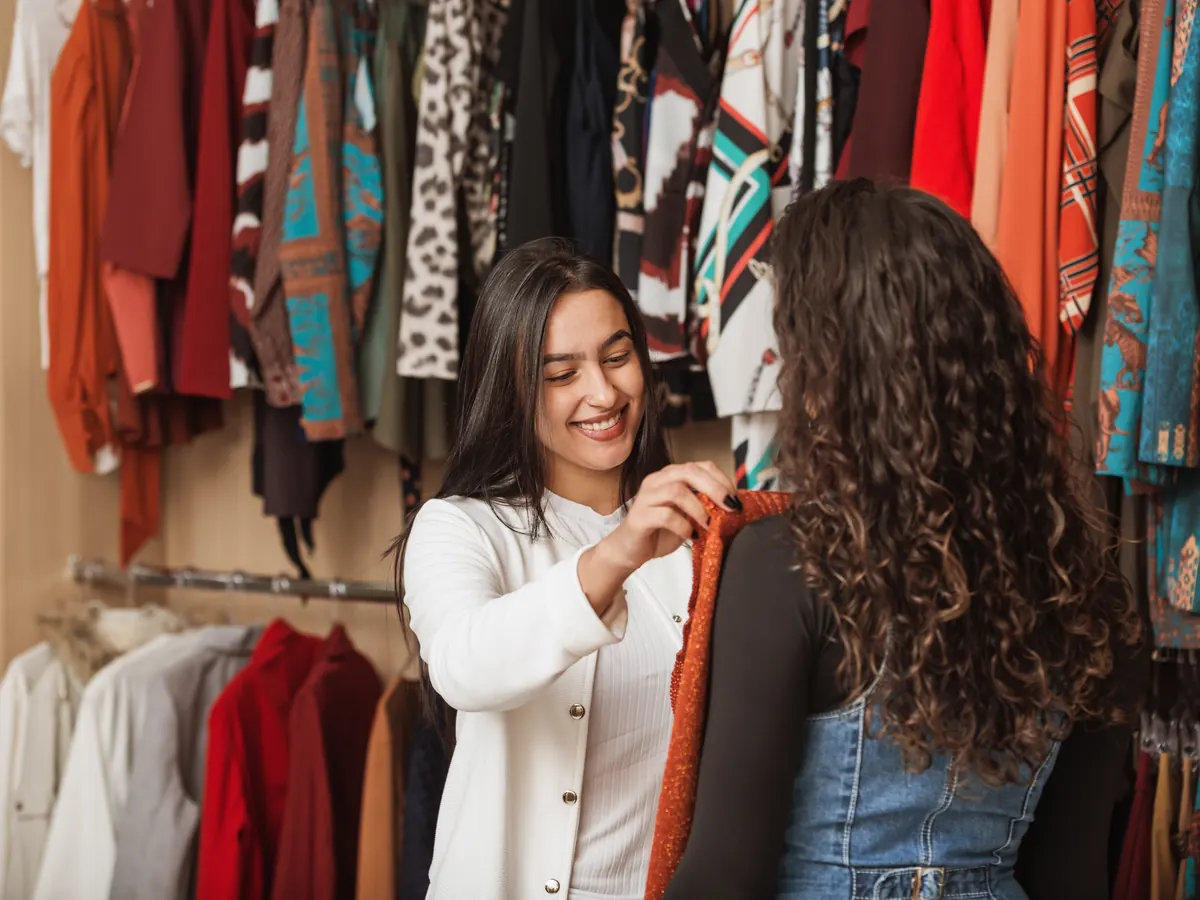 A shopper and a sales associate looking at clothes in a boutique.