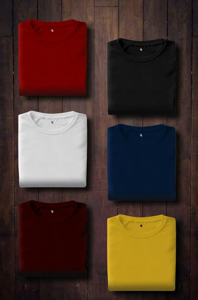 Folded T-shirts in six colours on a wooden table.