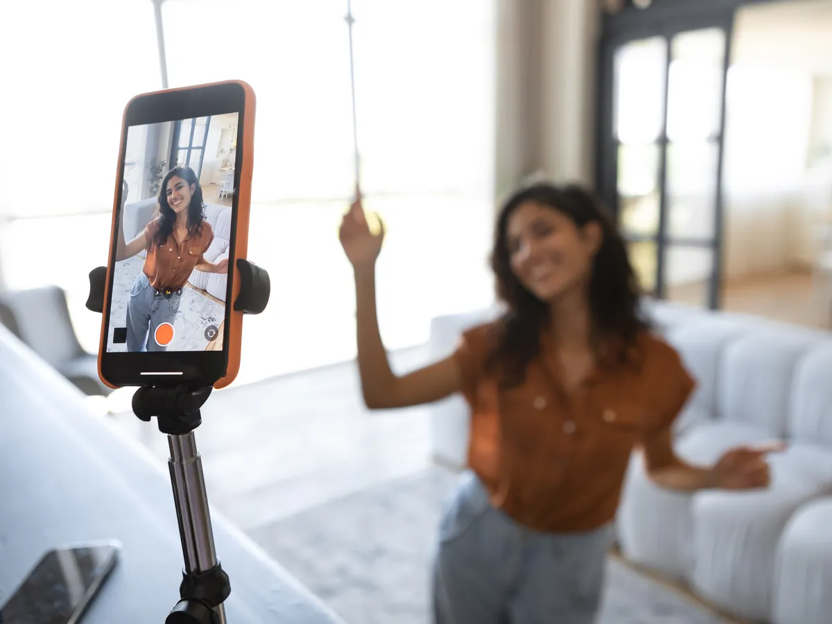 A creator filming herself on a phone on a tripod at home.