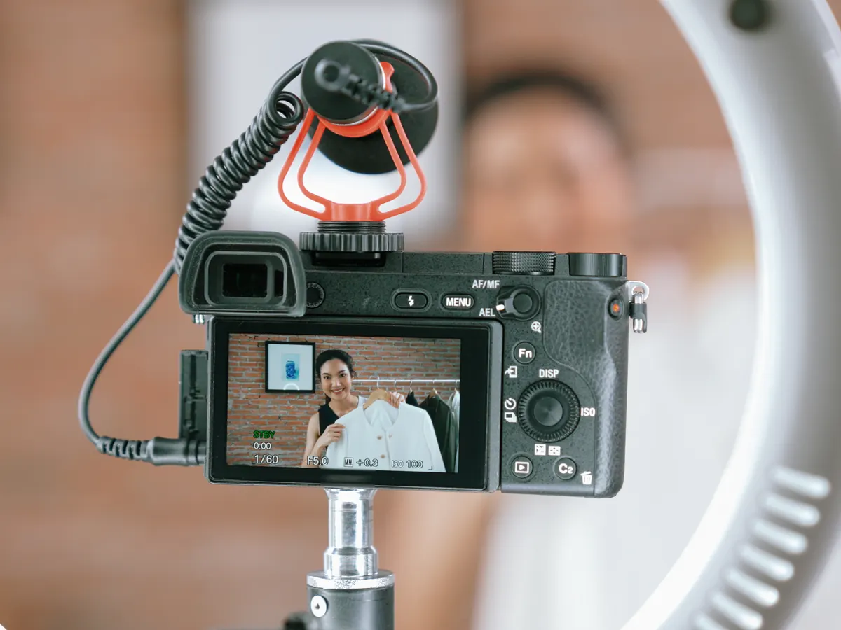 A camera on a ring light, filming a creator showing off a jacket.