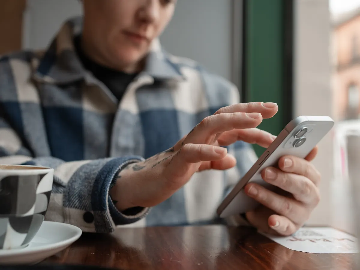 A woman scrolling social media on her phone in a café.