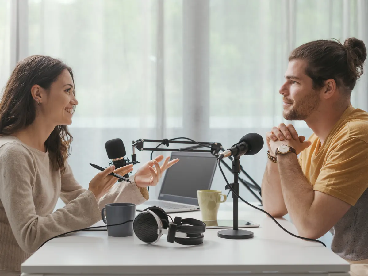 Two people recording a podcast interview at a table.