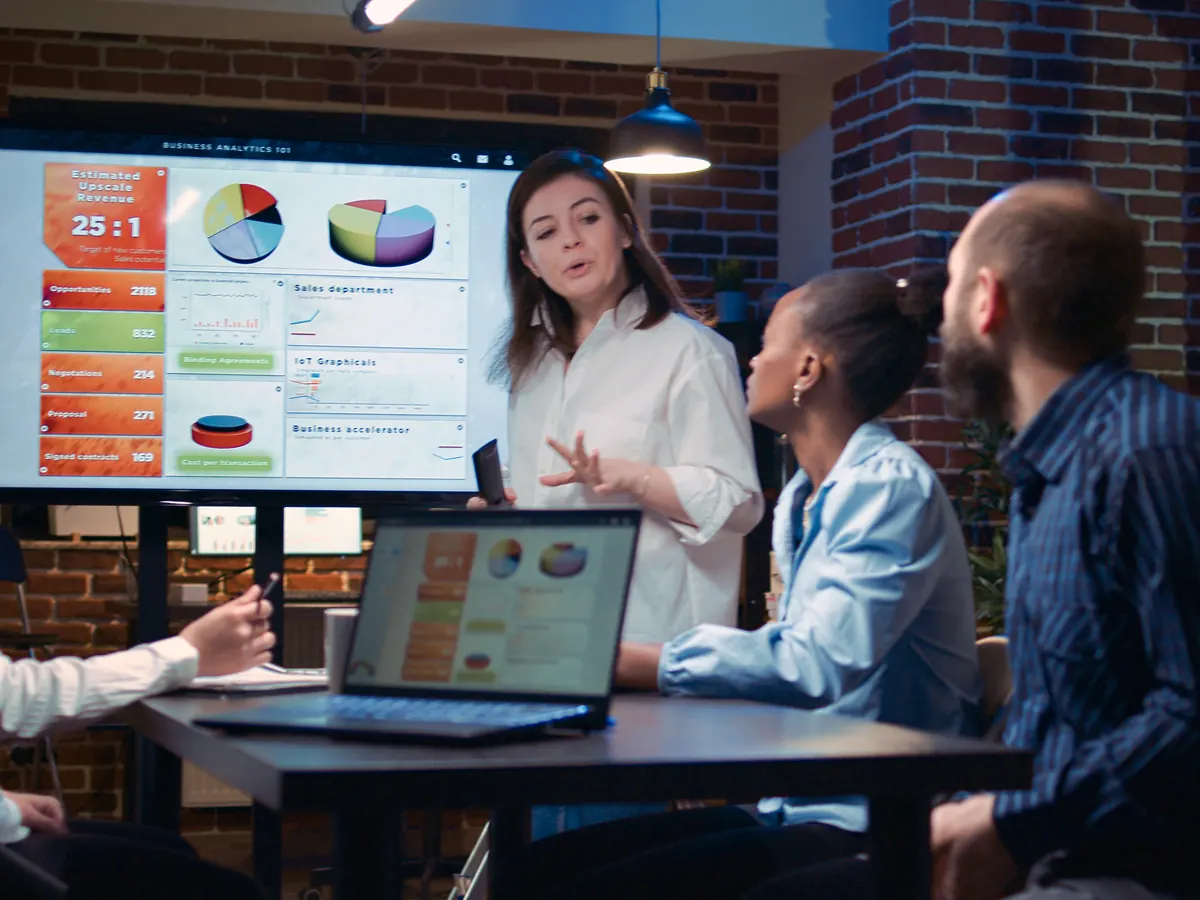 A team reviewing charts on a big screen in a meeting.