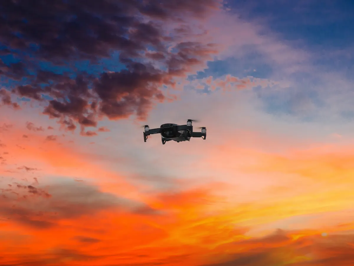 A drone flying against a sunset sky.