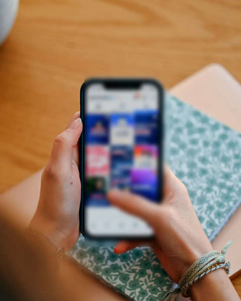 A hand scrolling a social feed on a phone.